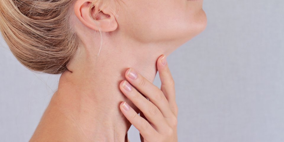 Frau fasst sich an den Hals