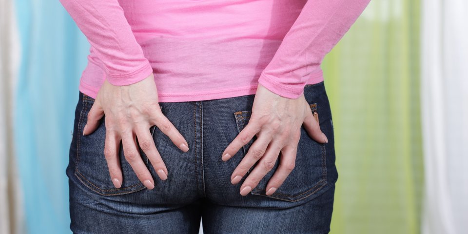 Frau in Jeans fasst sich ans Gesäß