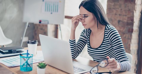 Frau mit Kopfschmerzen am Laptop
