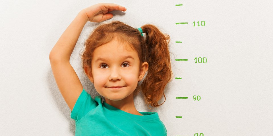 Fröhliches Kind misst seine Größe