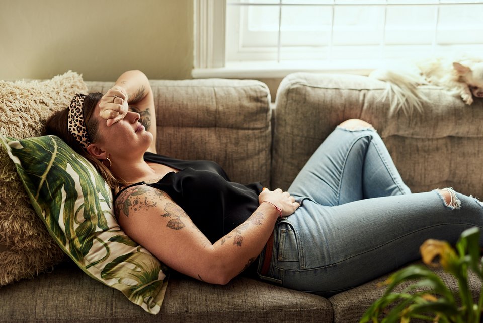 Frau liegt mit Schmerzen auf einer Couch