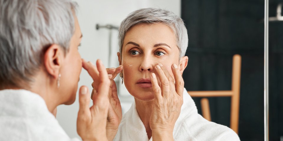 Frau betrachtet ihr Gesicht im Spiegel