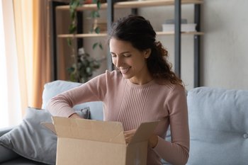Frau packt Paket aus - Infopaket Pflüger