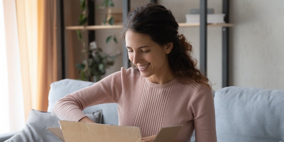 Frau packt Paket aus - Infopaket Pflüger